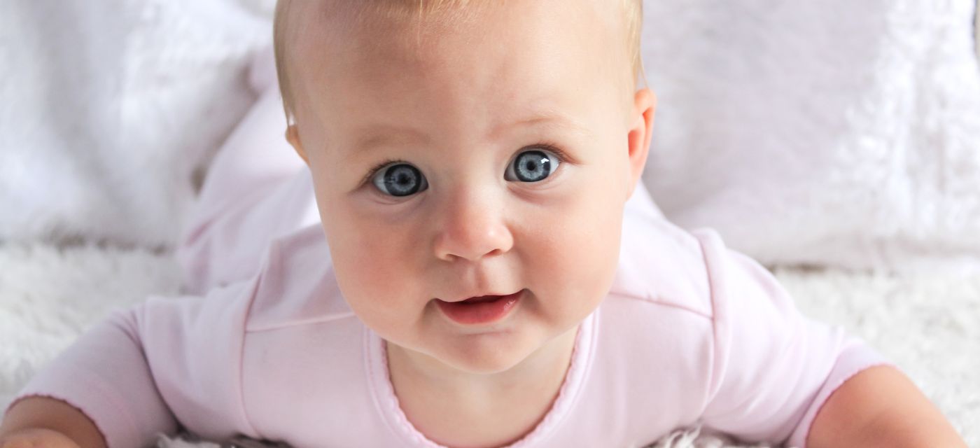 Baby with big blue eyes looking at camera.